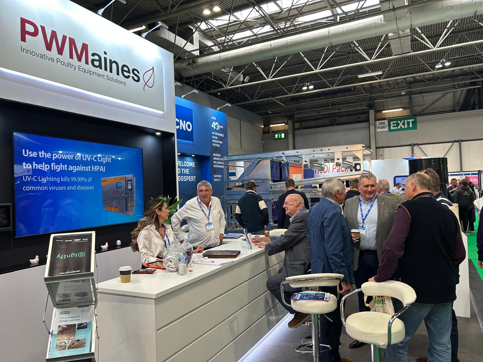 PW Maines showcasing poultry housing, lighting, and ventilation systems at an exhibition with visitors enquiring.